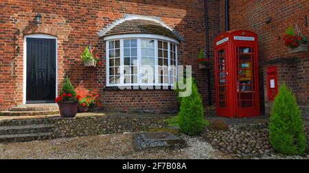 Alte Post mit roter Telefonbox mit Defibrillator und roter Briefbox. Stockfoto