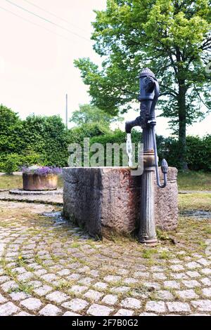 Wasser fließt an einem Frühlingstag aus einem Wasserpumpenbrunnen in einem Park in Winnweiler, Deutschland. Stockfoto