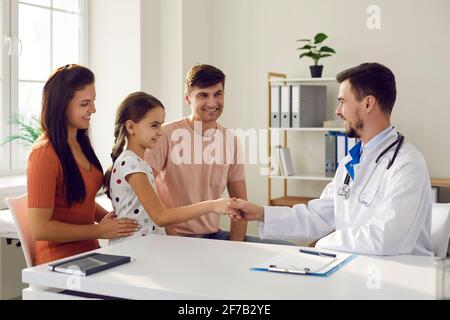 Das Kind schüttelt sich die Hände und trifft den Hausarzt, während es in der Arztpraxis sitzt. Stockfoto