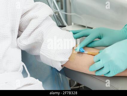 Die Kosmetikerin führt eine Nadel in die Vene des Patienten ein Blutentnahme für kosmetische Eingriffe und Plasmolifting Stockfoto