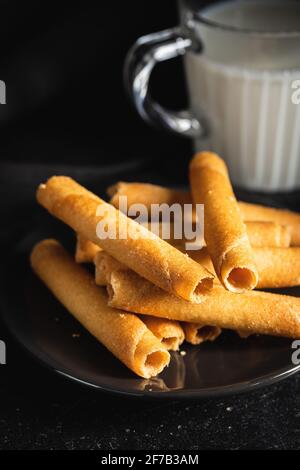 Süße Waffelröhrchen Rollen auf dem Teller auf dem schwarzen Tisch. Stockfoto