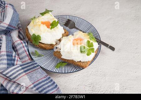 Auf einem hellen Hintergrund ein Teller mit einem Diät-Frühstück mit gebackenem Toast mit geschlagenen Eiern. Stockfoto