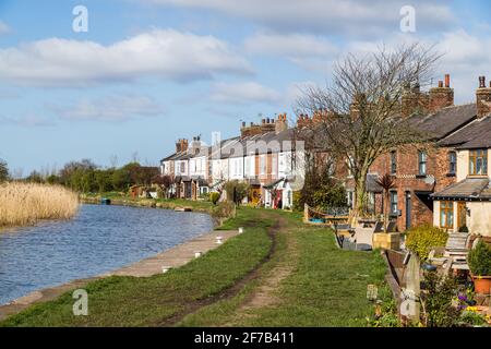 Reihe von Terrassenhäusern, die im April 2021 an einer Biegung des Leeds Liverpool Canal in der Nähe von Burscough, Lancashire, gesehen wurden. Stockfoto