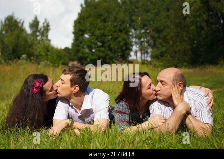 Russland. Vyborg 08.07.2013 Junge und ältere Paare küssen sich im Park, der auf dem Gras liegt. Hochwertige Fotos Stockfoto