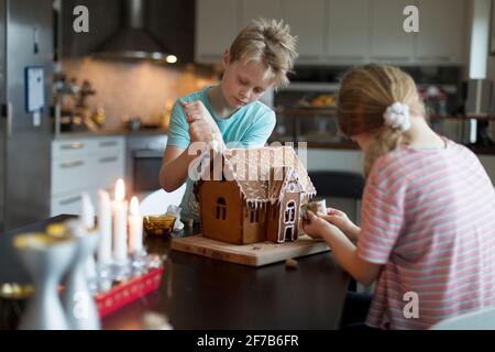 Kinder bereiten Lebkuchenhaus in der Küche Stockfoto