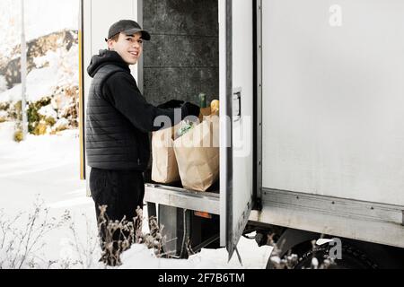 Mann, der Lebensmittel aus dem Kofferraum des Autos auslädt Stockfoto