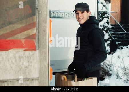 Mann, der Lebensmittel aus dem Kofferraum des Autos auslädt Stockfoto