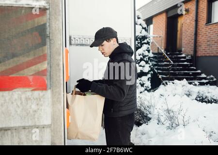 Mann, der Lebensmittel aus dem Kofferraum des Autos auslädt Stockfoto