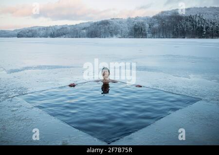 Mann, der in einem gefrorenen See schwimmte Stockfoto