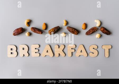 Gesundes Frühstück auf grauem Hintergrund, Draufsicht. Datteln und Nüsse mit Word-Frühstück. Rohkost und vegetarisches Konzept. Stockfoto