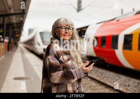 Reife Frau am Bahnhof Stockfoto