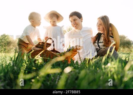 Glückliche Familie mit Kindern in der Natur im Sommer sitzt auf dem Gras. Stockfoto