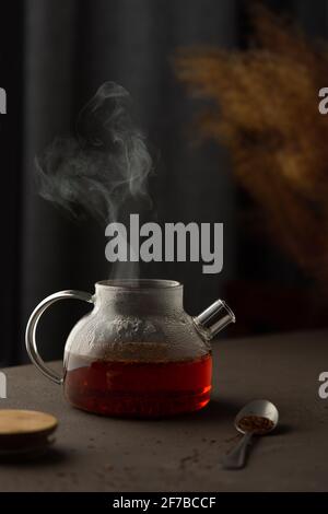 Der Prozess der Zubereitung von Rooibos-Tee mit Kräutern, Glas Teekannen mit koffeinfreiem Tee in kochendem Wasser getränkt, steigt der Dampf über die Teekannen Stockfoto