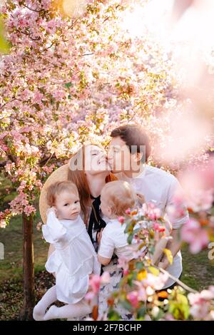 Porträt einer glücklichen und gesunden Familie auf dem Hintergrund eines blühenden Apfelbaums im Garten. Stockfoto