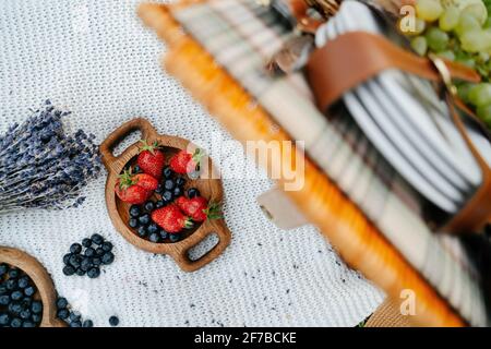 Gesunde, leckere Früchte Erdbeeren und Heidelbeeren in einem Holzteller auf einer Strickdecke. Stockfoto