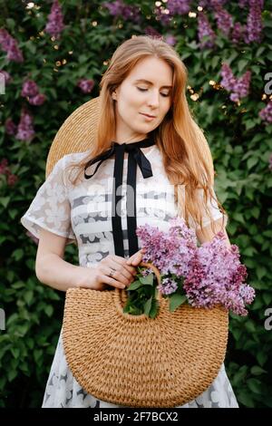 Porträt einer schönen jungen Frau mit roten Haaren, die Blumen auf einem Feld gesammelt hält. Stockfoto