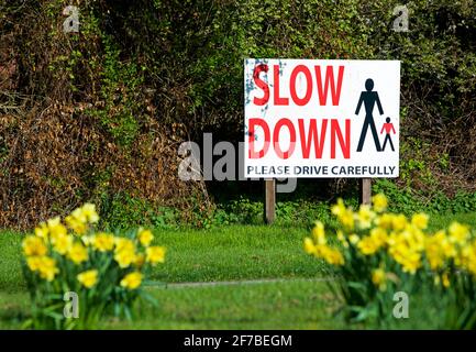 Schild fordert Fahrer auf, durch das Dorf, England, zu verlangsamen Stockfoto