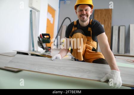 Lächelnder Meister im Hut hält Laminatbrett Stockfoto