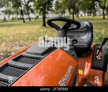Ho Chi Minh City, 16. März 2021: Gebrauchte orange Reiten Rasenmäher auf dem Gras im Park, Nahaufnahme. Stockfoto