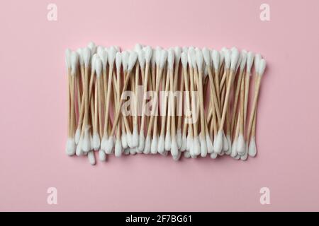 Oberansicht eines Bündels aus Holzwattestäbchen mit weißen Spitzen, die in einer Reihe auf einem rosa Hintergrund angeordnet sind, umweltfreundliches Hygienekonzept Stockfoto