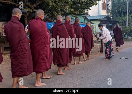 Mönche, die in den Straßen von Bago spazieren und Lebensmittelspenden sammeln, Bago, Myanmar Stockfoto