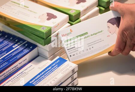 Berlin, Deutschland. April 2021. ABBILDUNG - mehrere Corona-Selbsttests liegen auf einem Tisch. Eine Frau nimmt einen der schnellen Antigen-Tests. Quelle: Kira Hofmann/dpa-Zentralbild/ZB/dpa/Alamy Live News Stockfoto