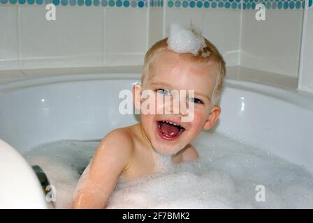 Drei Jahre alter Junge, der in einer Badewanne sitzt Stockfoto