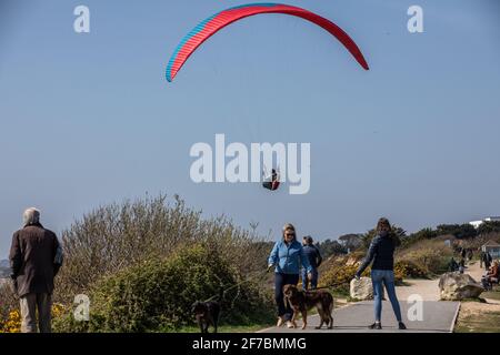 Paragleiter fliegen an einem windigen Tag entlang der Südwestküste der englischen Riviera, Dorset, England, Großbritannien, über den Strand von Highcliffe. Stockfoto