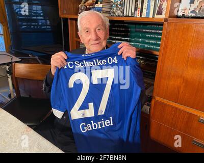 Jerusalem, Israel. März 2021. Gabriel Bach, der damalige Chefankläger der Eichmann-Prozesse, hält ein Fanshirt mit seinem Vornamen hoch, das ihm das Team des FC Schalke 04 bei einem seiner Deutschlandaufenthalte geschenkt hatte. Bach ist seit seiner Kindheit in Berlin Fan des Clubs, weil seine Farben ihn an die jüdische Jugendbewegung Blau und Weiß erinnert hatten. (An dpa: '60 Jahre nach dem Eichmann-Prozess: Staatsanwalt Gabriel Bach erinnert sich') Quelle: Sara Lemel/dpa/Alamy Live News Stockfoto