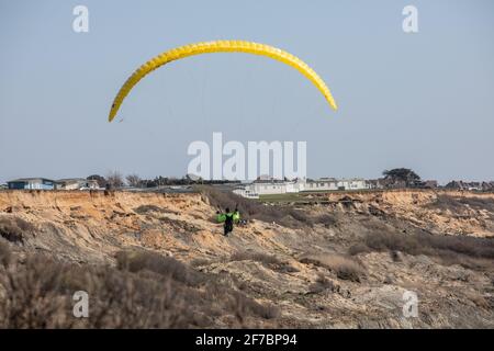 Paragleiter fliegen an einem windigen Tag entlang der Südwestküste der englischen Riviera, Dorset, England, Großbritannien, über den Strand von Highcliffe. Stockfoto