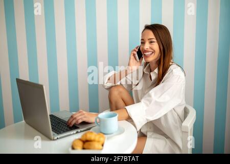 Glückliche schöne Frau, die mit Laptop-Computer zu Hause im Büro. Remote Job Lockdown Work Konzept. Stockfoto