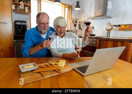 COVID-19 Bleiben Sie in Verbindung und hoffen Konzept. Happy Senior Paar mit Wein Video-Anruf Freunde auf dem Laptop oder Online-Chat mit der Familie feiern eas Stockfoto