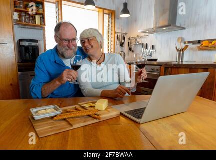 COVID-19 Bleiben Sie in Verbindung und hoffen Konzept. Happy Senior Paar mit Wein Video-Anruf Freunde auf dem Laptop oder Online-Chat mit der Familie feiern eas Stockfoto
