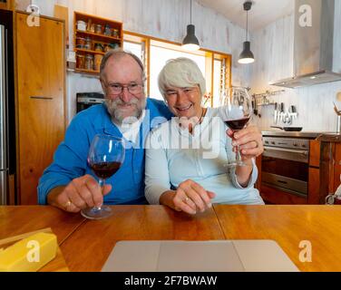 COVID-19 Bleiben Sie in Verbindung und hoffen Konzept. Happy Senior Paar mit Wein Video-Anruf Freunde auf dem Laptop oder Online-Chat mit der Familie feiern eas Stockfoto