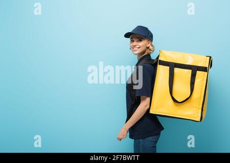 Hübscher Kurier mit Thermorucksack, der die Kamera blau anlächelt Stockfoto