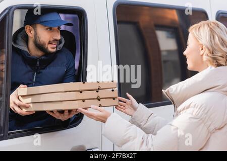 arabischer Lieferer im LKW, der Blondine Pizzakisten gab Frau Stockfoto