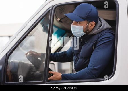arabischer Mann in medizinischer Maske, der während der Fahrt nach vorne schaut LKW Stockfoto