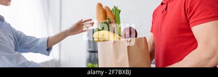 Beschnittene Ansicht einer Frau, die Papiertüte mit frischen Lebensmitteln vom Lieferer, Banner, nahm Stockfoto