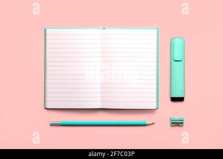 Offenes Tagebuch mit Kopierraum, blauem Stift, Textmarker blauem Marker und Blauer Bleistiftspitzer auf einem rosa Hintergrund.Arbeitsplatz Schreibtisch Stockfoto