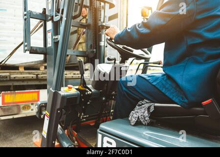 Ein Mann auf einem Gabelstapler arbeitet in einem großen Lager, lädt Säcke von Rohstoffen Stockfoto