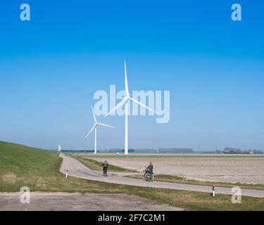 Menschen auf Fahrrad und Windkraftanlagen in der ländlichen Landschaft von schouwen duiveland in der niederländischen Provinz zeeland Stockfoto