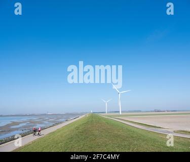 Männer auf Fahrrad und Windkraftanlagen in der ländlichen Landschaft von schouwen duiveland in der niederländischen Provinz zeeland Stockfoto