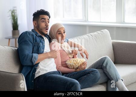 Schockiert muslimische Paar beobachten Thriller, Zuhause innen Stockfoto