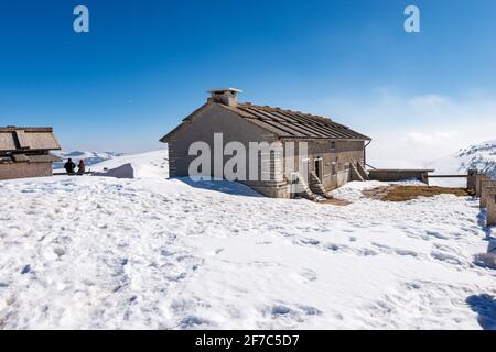 Typisches altes Bauernhaus aus Stein und Kuhstall auf dem Plateau von Lessinia im Winter mit Schnee in der Nähe des Gipfels von Corno d'Aquilio. Sant'Anna d'Avaedo, Venetien, Italien. Stockfoto