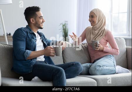 Junges muslimisches Paar, das Kaffee trinkt und zu Hause ein Gespräch führt Stockfoto