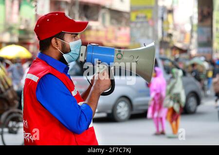 Dhaka, Bangladesch - 06. April 2021: Freiwillige der Red Crescent Society warnen Fußgänger vor dem Tragen von Masken im Maghbazar in Dhaka, dem zweiten d Stockfoto