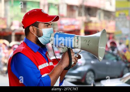 Dhaka, Bangladesch - 06. April 2021: Freiwillige der Red Crescent Society warnen Fußgänger vor dem Tragen von Masken im Maghbazar in Dhaka, dem zweiten d Stockfoto