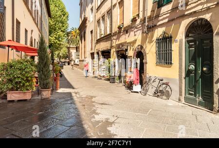 Lucca, Toskana, Italien - 3. Juli 2019: Alte enge mittelalterliche Straße mit Bar und Geschäften im historischen Zentrum der Altstadt von Lucca Stockfoto