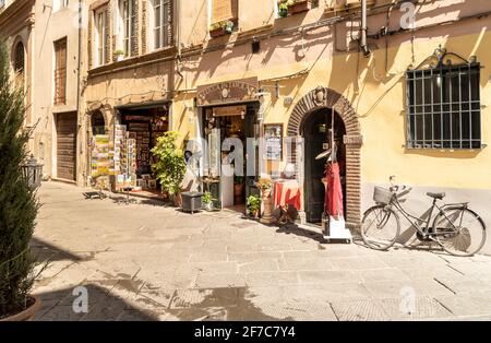 Lucca, Toskana, Italien - 3. Juli 2019: Alte enge mittelalterliche Straße mit Bar und Geschäften im historischen Zentrum der Altstadt von Lucca Stockfoto