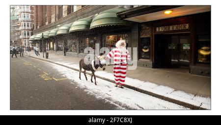 Vater Weihnachten und sein Seesel Dino posieren für Fotos vor einem schneebedeckten Harrods, bevor sie die Gäste am 9. August 2005 in London, England, im dritten Stock des Knightsbridge Stores auf eine Tour durch die Weihnachtswelt nehmen. Über 15.000ft qm Fläche sind Weihnachten im gesamten Geschäft gewidmet. Mit einer künstlichen Schneemaschine, die gegen die Sommerwärme kämpft, kommen Pater Christmas und sein Seesel Dino vor einem schneebedeckten Eingang nach Harrods zum Start von Christmas World im Knightsbridge Store in London an. Bild David Sandison 9/8/2005 Stockfoto